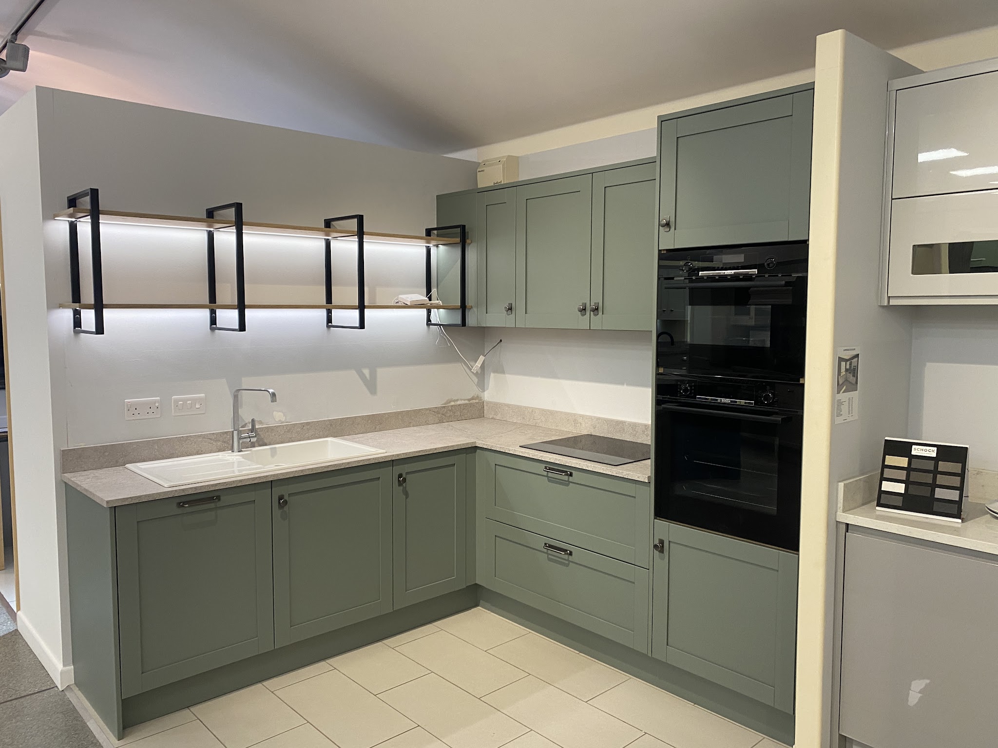 Sage green shaker kitchen with open shelving on black brackets
