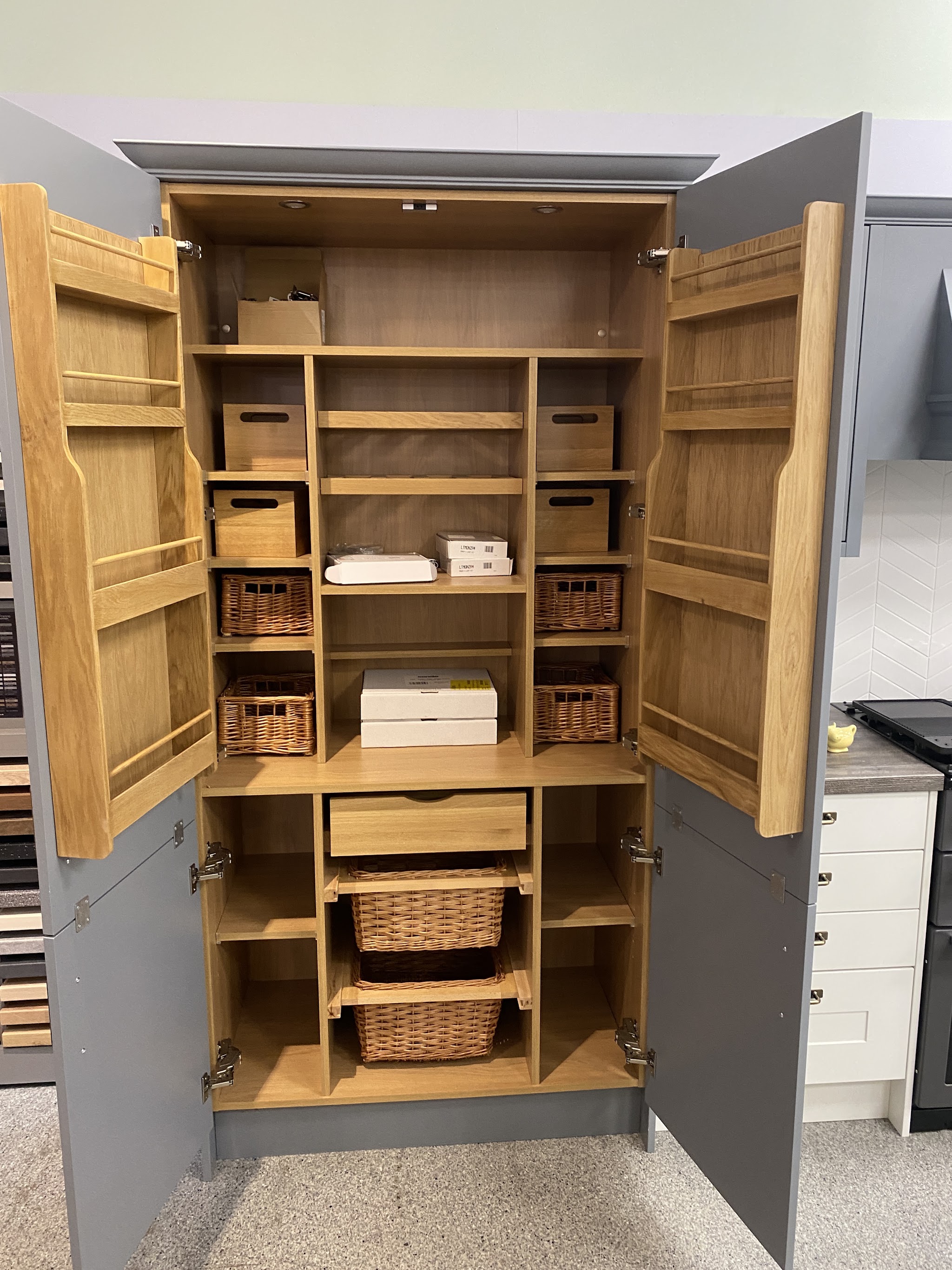 Larder cupboard with oak interior, spice racks on the doors and wicker baskets