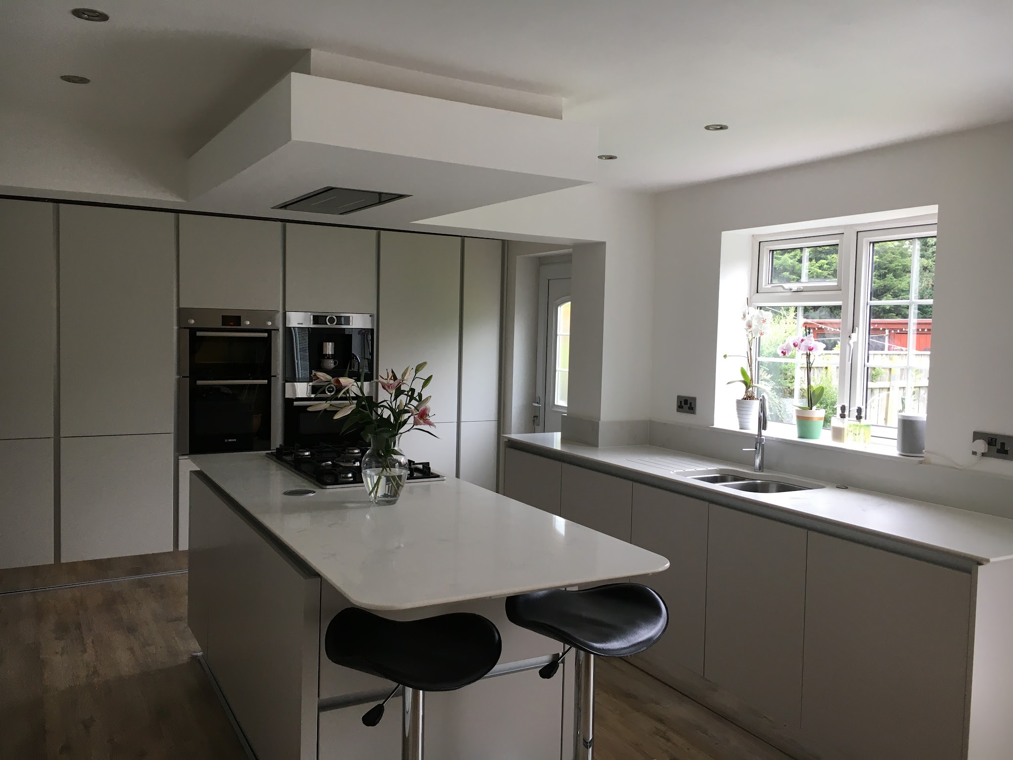 Grey handleless kitchen with a white island and bar stools