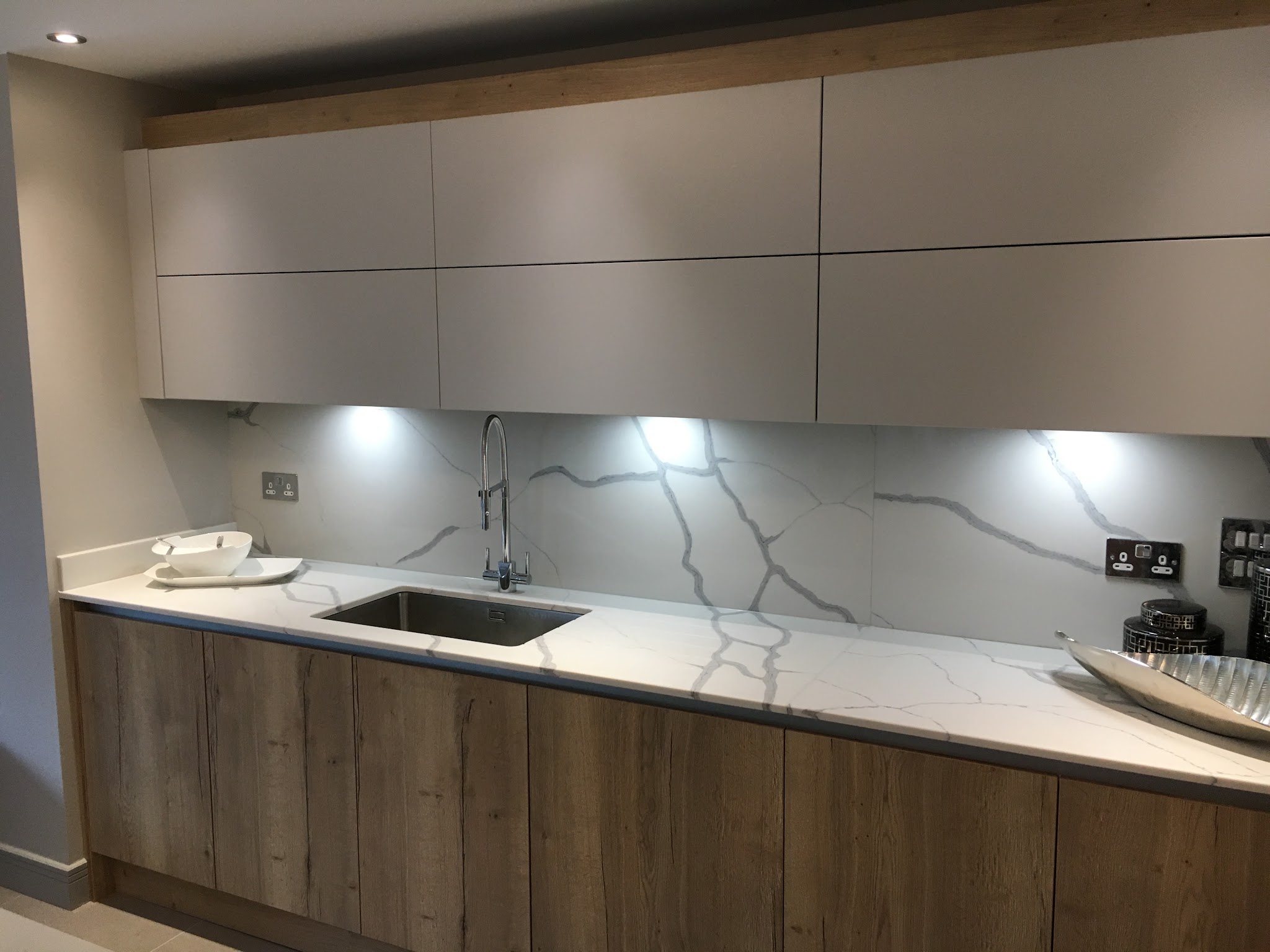 Rustic oak-effect base units under grey wall cupboards with a marble-look splashback