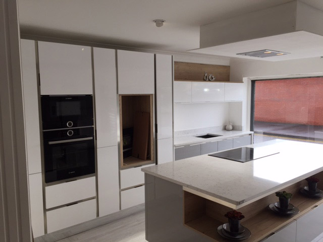 White handleless kitchen with an island and open oak shelf