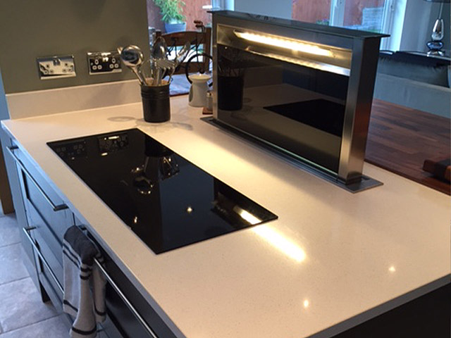 Induction hob with a pop-up downdraft extractor in a quartz island