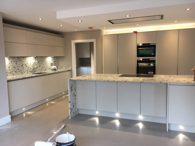Handleless kitchen with marble-look island and plinth lighting